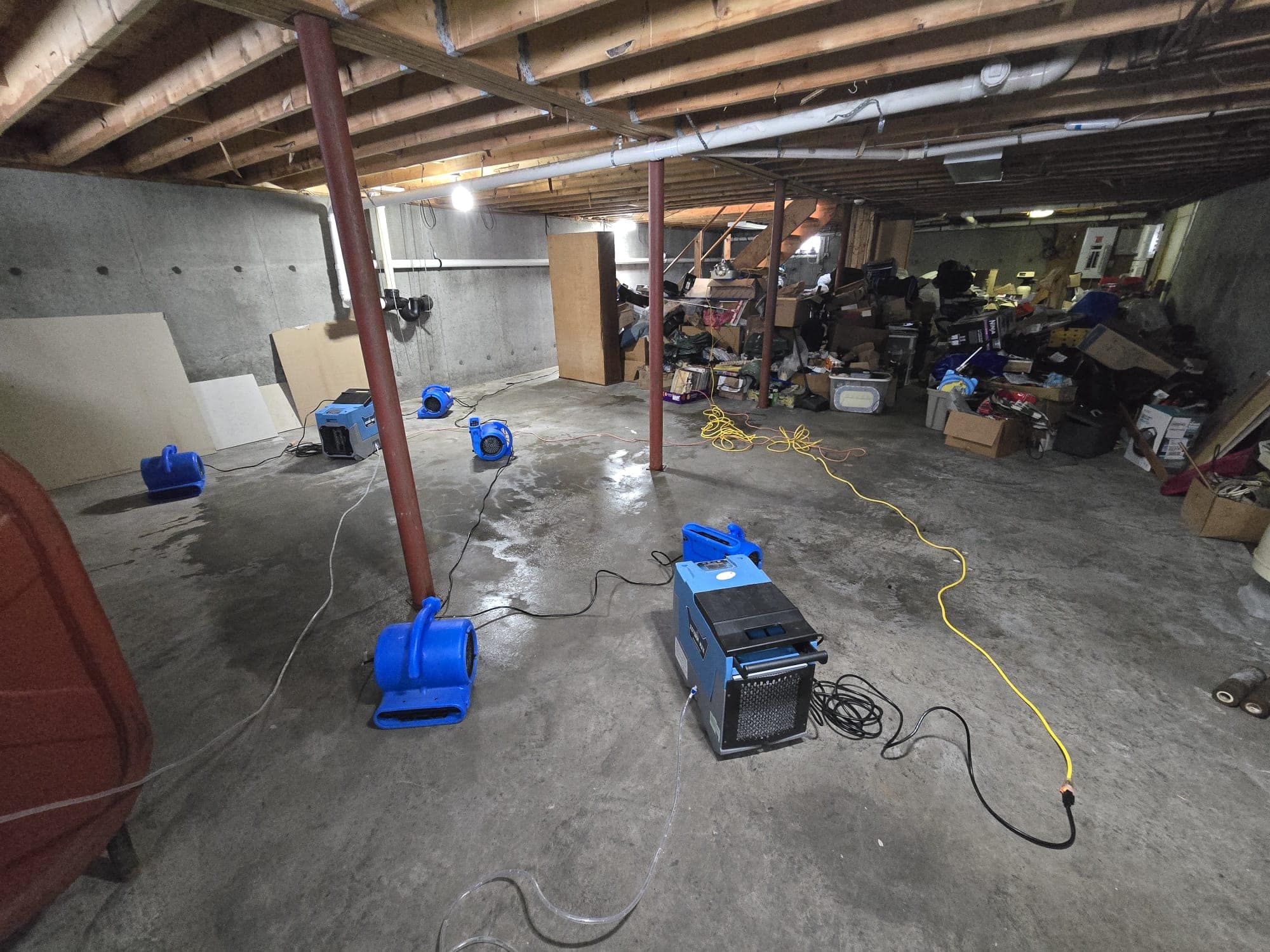 Air movers and an LGR dehumidifier drying a wet concrete basement slab