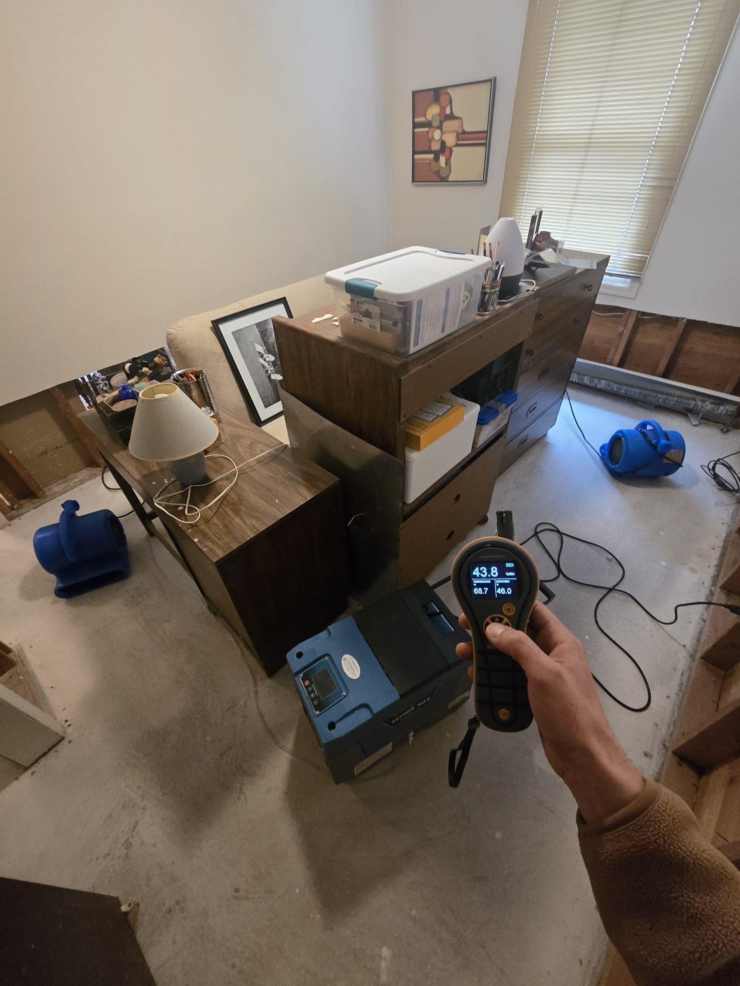 Thermo-hygrometer confirming 43.8 percent humidity in a bedroom drying with air movers